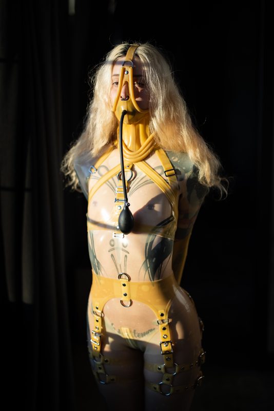 A sexy photograph of Cam Damage in transparent latex. Tagged with: gagged & neck corset. Posted April 2021.