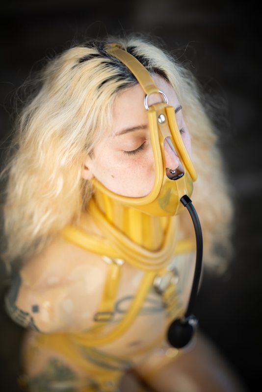 A sexy photograph of Cam Damage in transparent latex. Tagged with: gagged, neck corset & armbinder. Posted April 2021.