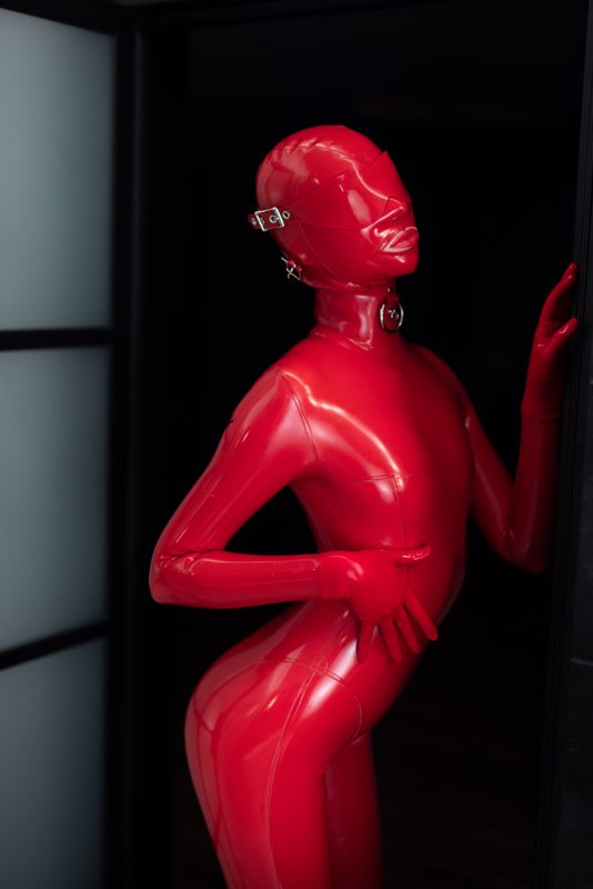 A sexy photograph of Defiantly Yours in red latex. Posted March 2023.