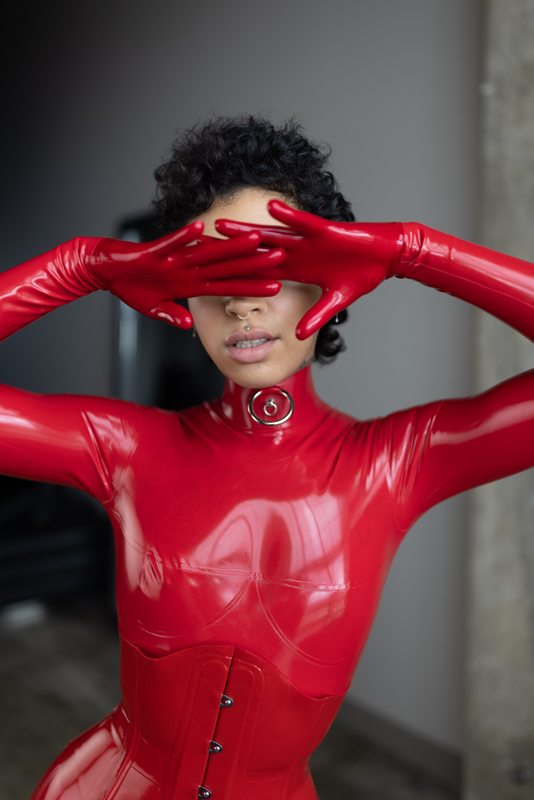 A sexy photograph of Ravyn Alexa, in red latex. Posted July 2021.