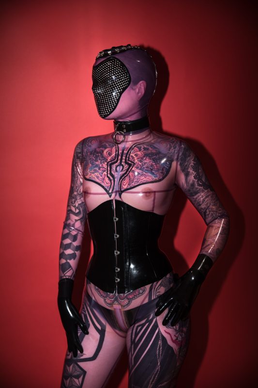 A sexy photograph of Fire Rabbit, in transparent & purple & pink latex. Tagged with: tattoos. Posted December 2017.