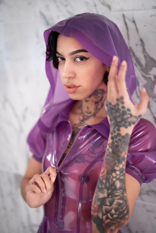 A sexy photograph of Ravyn Alexa in purple & pink & transparent latex. Posted May 2022.