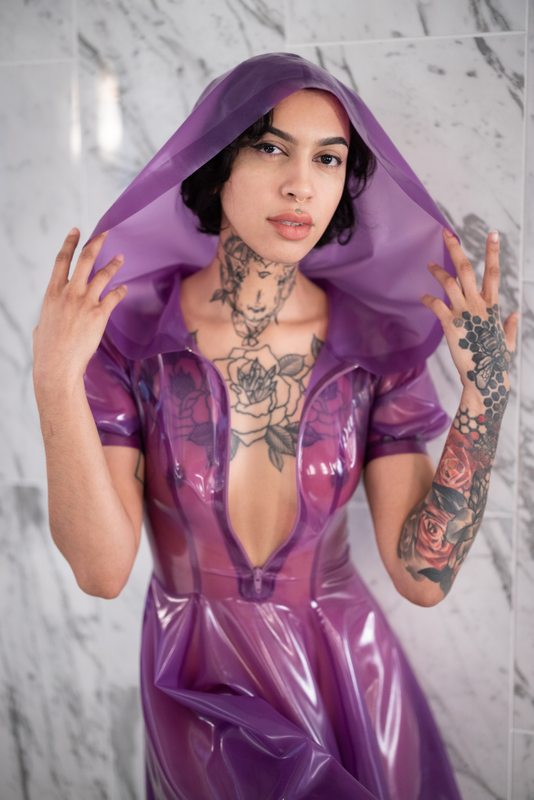 A sexy photograph of Ravyn Alexa in purple & pink & transparent latex. Posted April 2022.