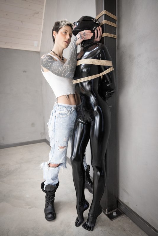 A sexy photograph of Vespa & Cam Damage in black latex. Tagged with: rope / shibari. Posted December 2021.