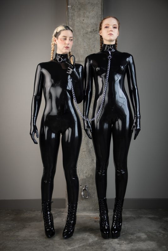 A sexy photograph of Cam Damage & Mbot in black latex. Posted July 2021.