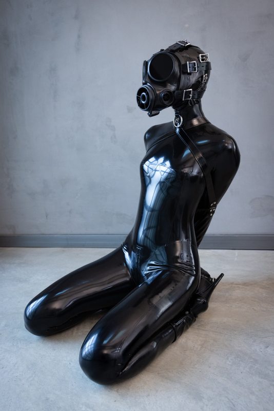A sexy photograph of Ravyn Alexa, in black latex. Tagged with: armbinder & gasmask. Posted December 2021.